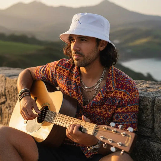 homme portant le bob en coton bio bakea coloris blanc en jouant de la guitare sur la côte basque