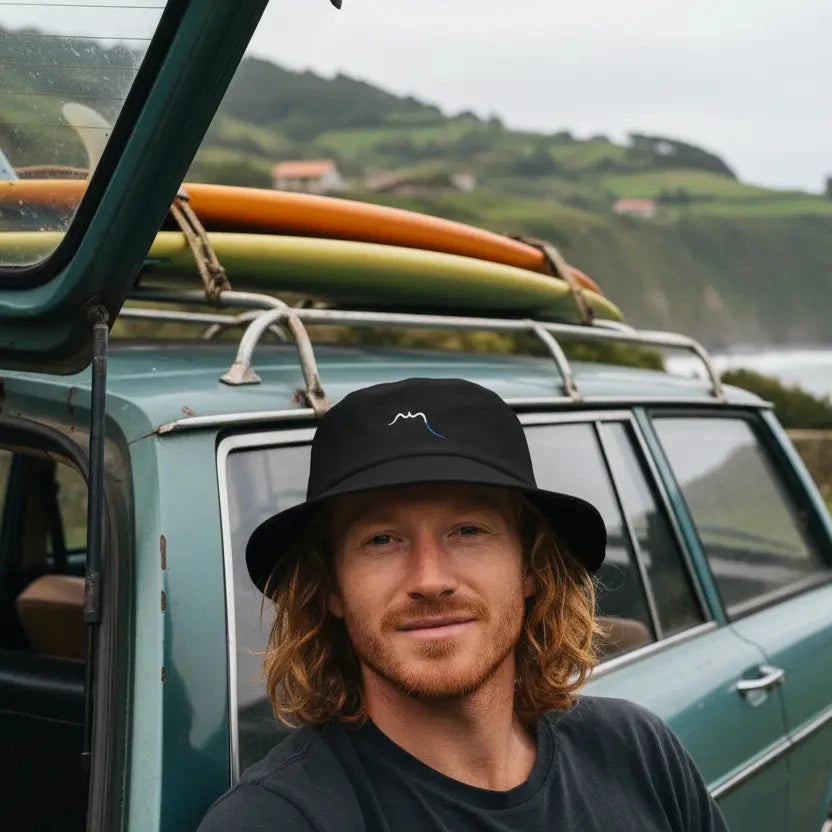 homme portant le bob en coton old school emeki coloris noir devant un spot de surf
