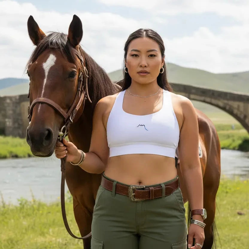 femme portant la brassière de sport éco-responsable carlina coloris blanc avec un cheval au bord d'une rivière