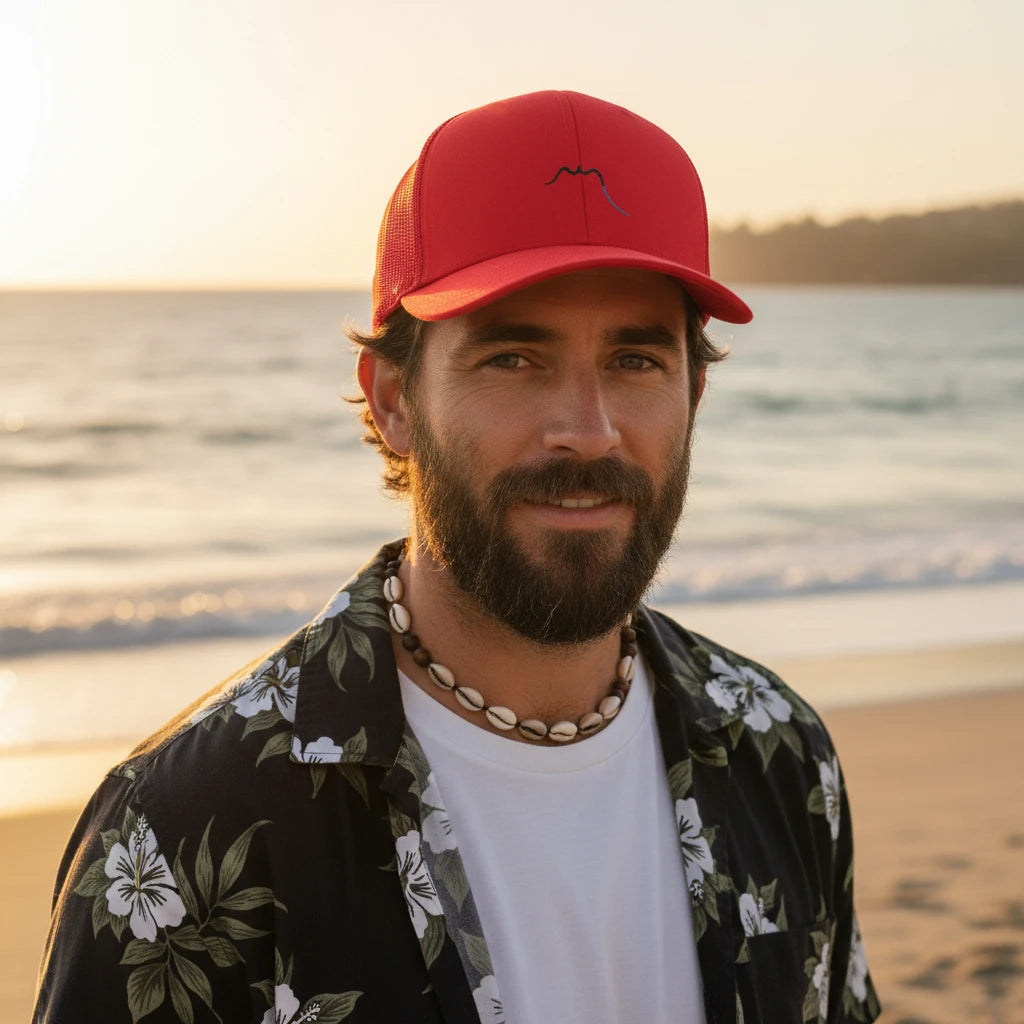 homme portant la casquette de camionneur respirante légère et réglable coloris rouge avec logo noir à la plage