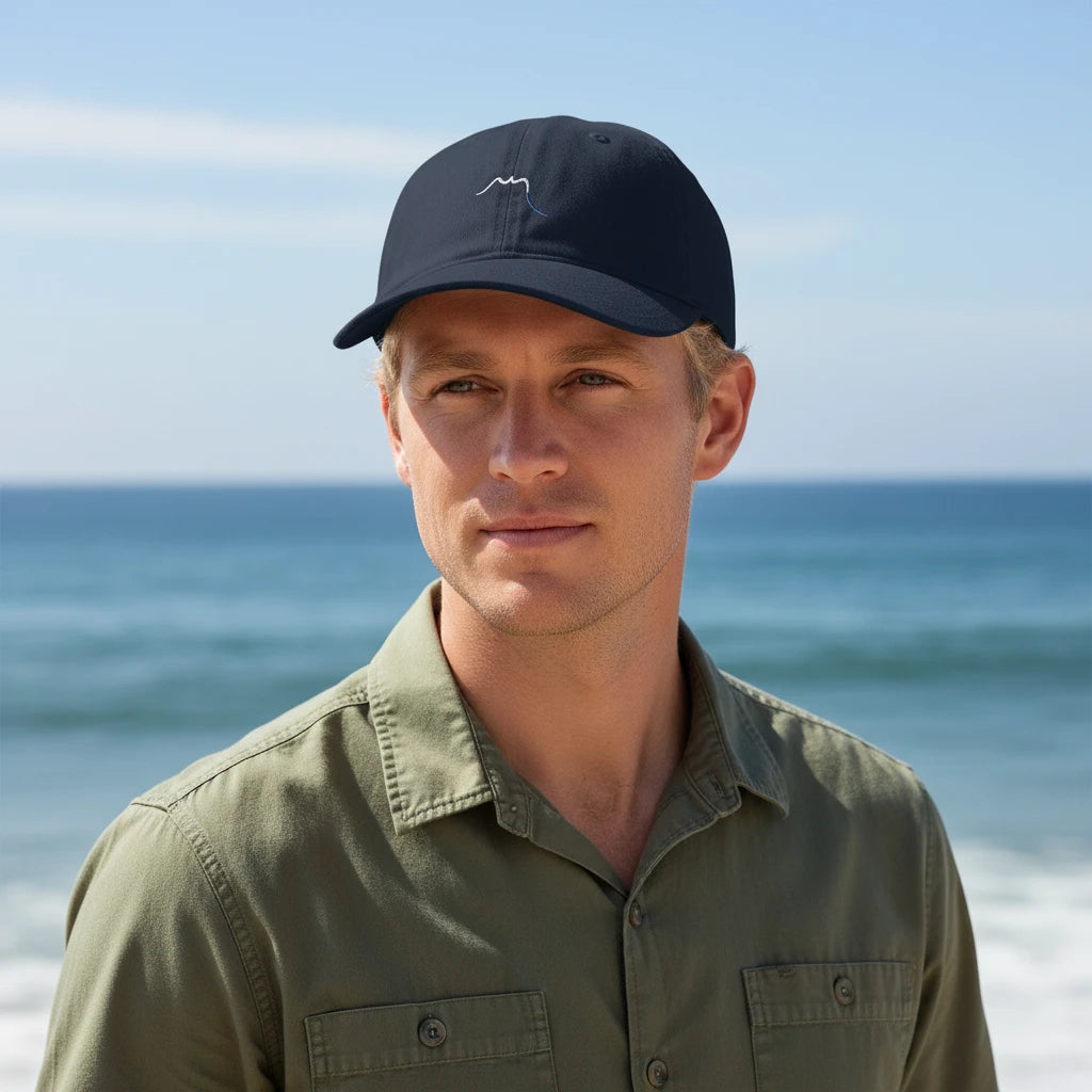 homme portant la casquette éco responsable en coton bio réglable coloris bleu marine devant l'océan