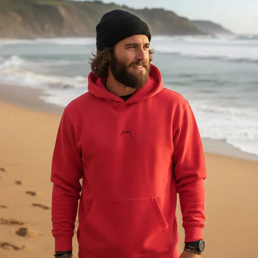 homme portant le hoodie negua coloris rouge logo noir sur une plage