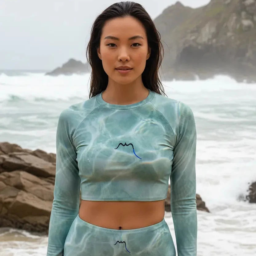femme portant le bikini de surf uhaina crop top manches longues motif eau sur une plage