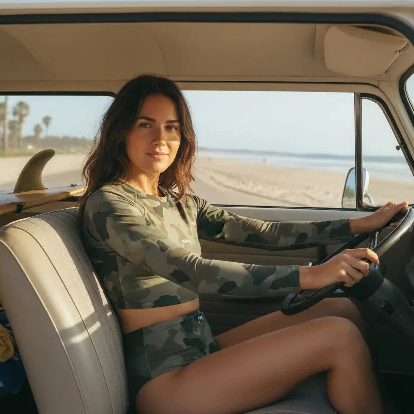 femme portant le bikini de surf uhaina crop top manches longues motif camo kaki au volant de son van 