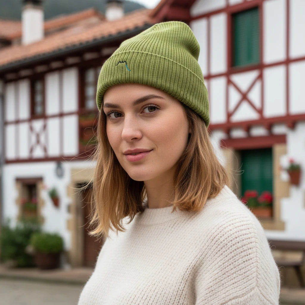 femme portant le bonnet côtelé brodé en coton bio travis coloris vert pistache dans un village basque