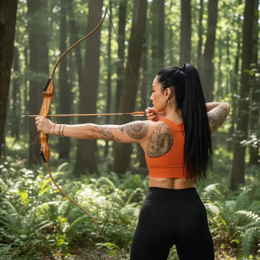 femme portant la brassière de sport éco-responsable carlina coloris orange qui tire à l'arc dans les bois