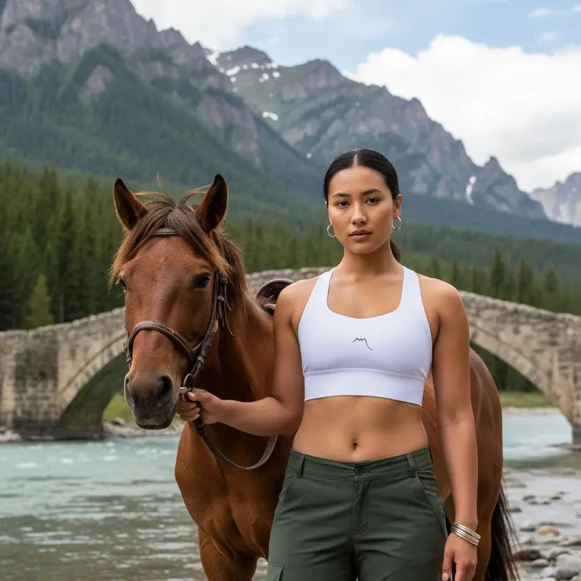 femme portant la brassière de sport éco-responsable carlina coloris blanc avec un cheval en pleine nature