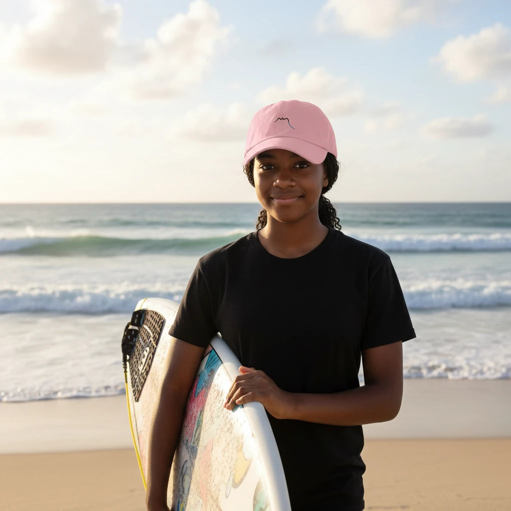 fille portant la casquette de baseball en  sergé de coton réglable coloris rose pâle à la plage avec une planche de surf