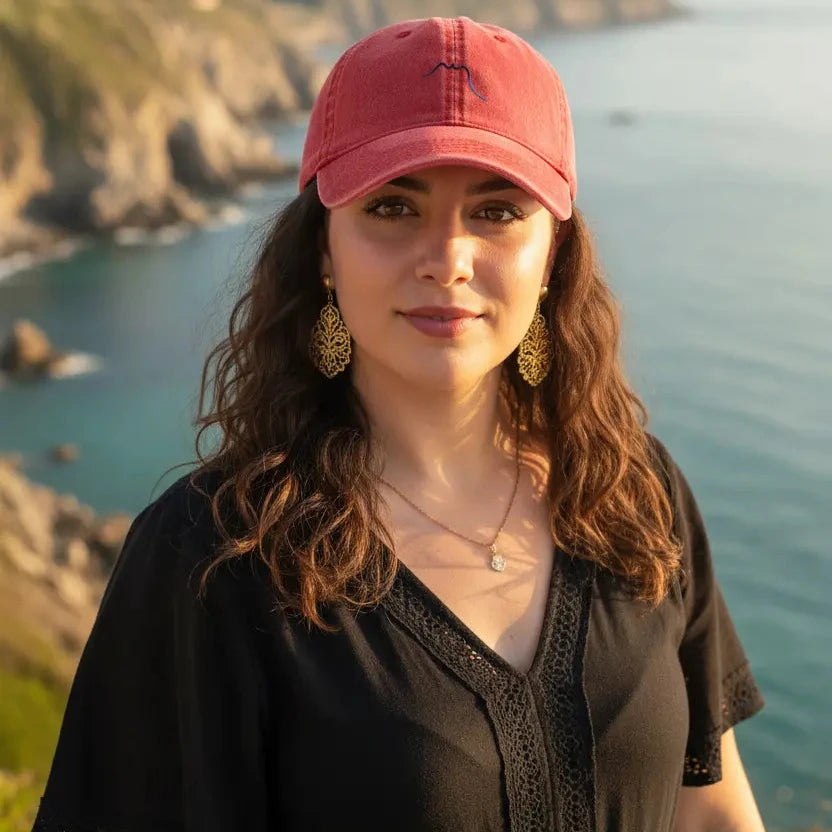 femme portant la casquette vintage en sergé de coton réglable coloris rouge devant l'océan