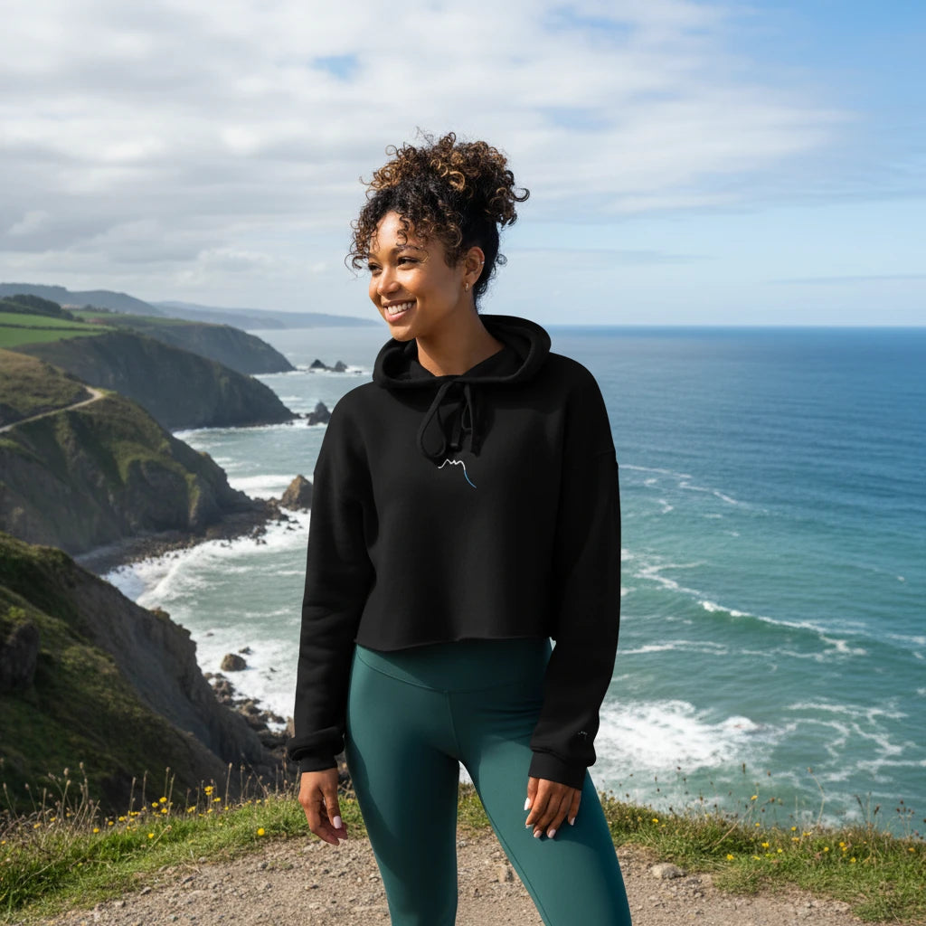 femme portant le crop-top hoodie brodé lesaka coloris noir devant l'océan
