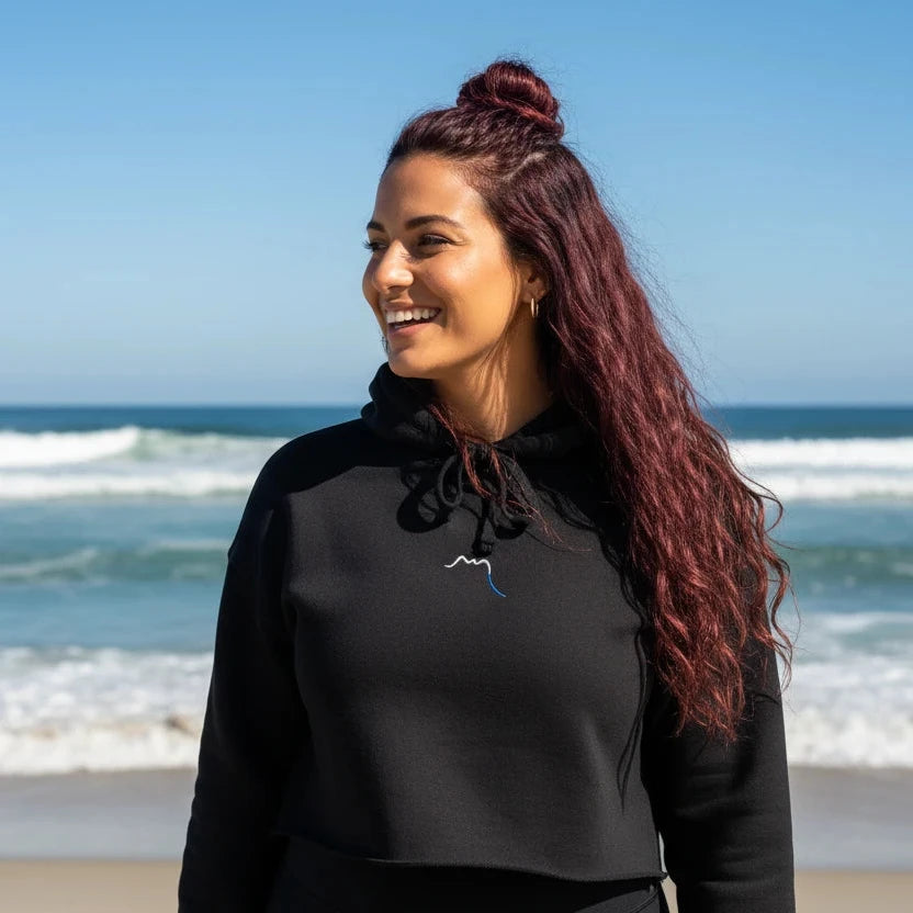 femme portant le crop-top hoodie brodé lesaka coloris noir à la plage