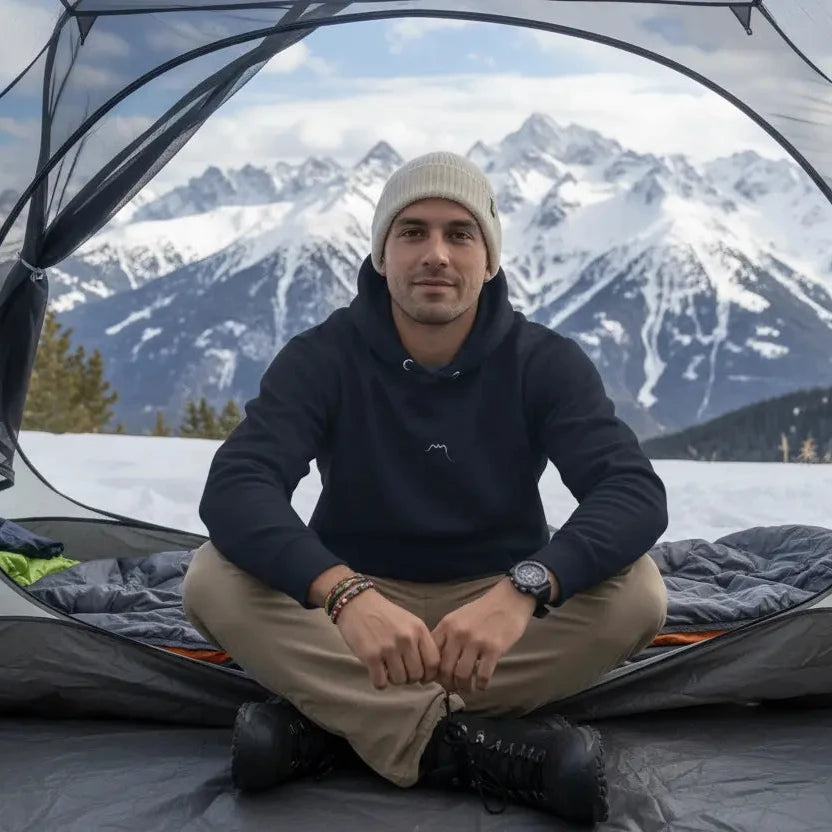 homme portant le hoodie en coton bio negua coloris bleu marine dans une tente de camping à la montagne