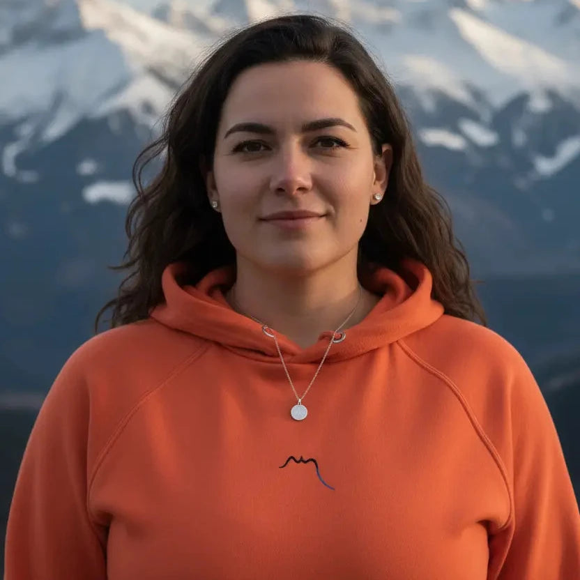 femme portant le hoodie sweat à capuche femme homme en coton biologique hotza coloris orange à la montagne 