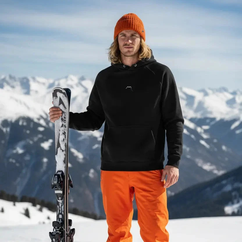 homme portant le hoodie sweat à capuche femme homme en coton biologique hotza coloris noir au ski à la montagne