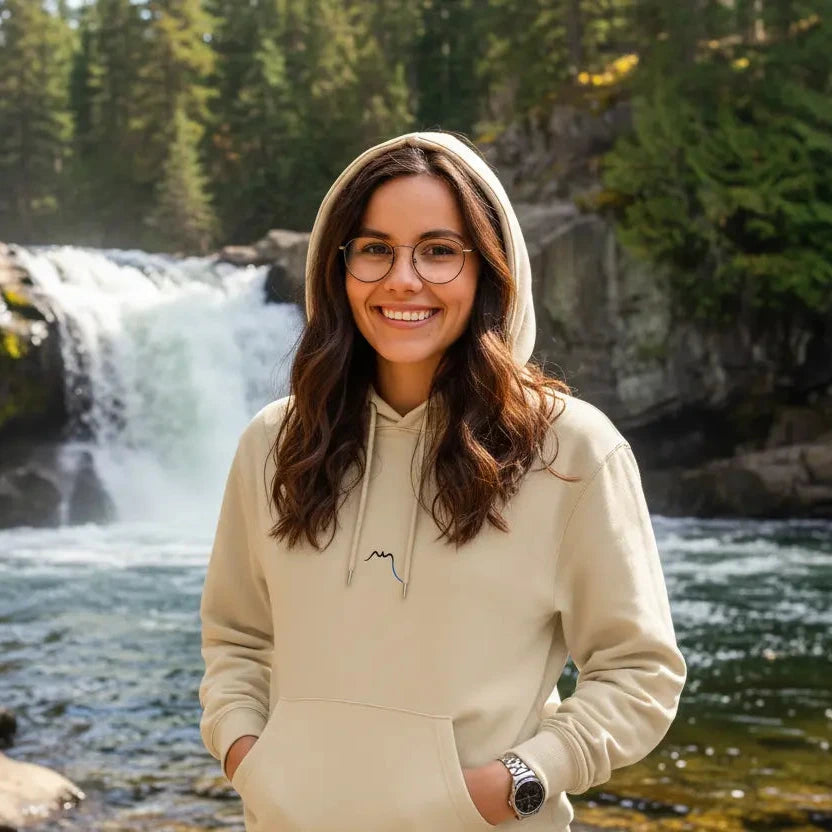femme portant le hoodie sweat à capuche en coton bio ekaitza coloris beige devant une rivière