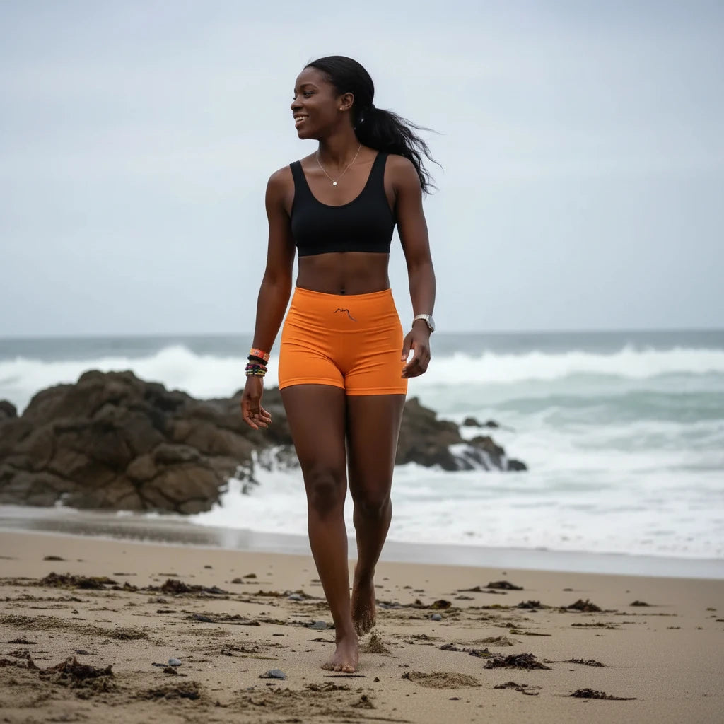 femme portant le legging short coloris orange à la plage