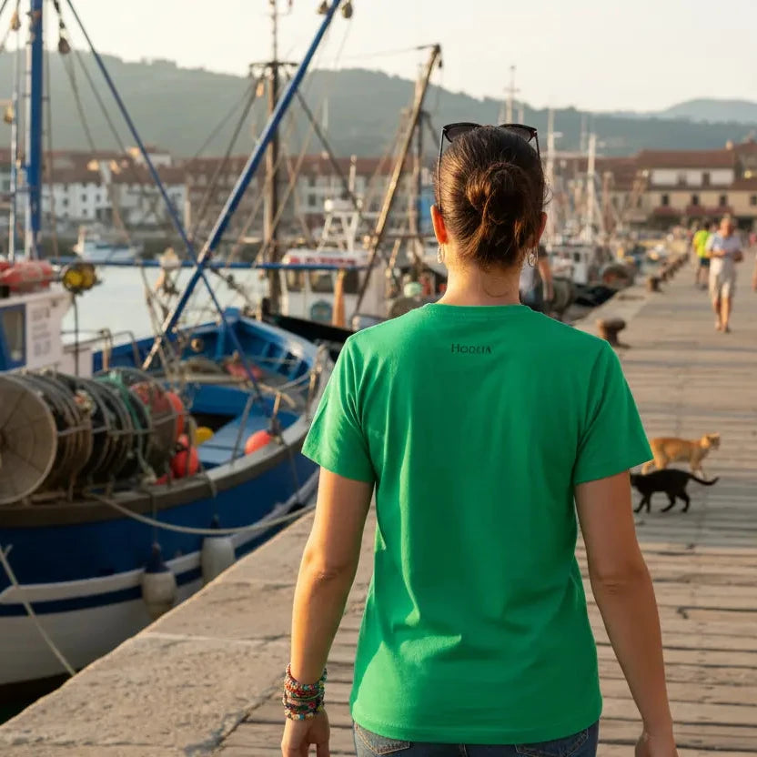 femme portant le t-shirt coton cintré femme insola coloris vert logo noir dans un port de pêche du pays basque
