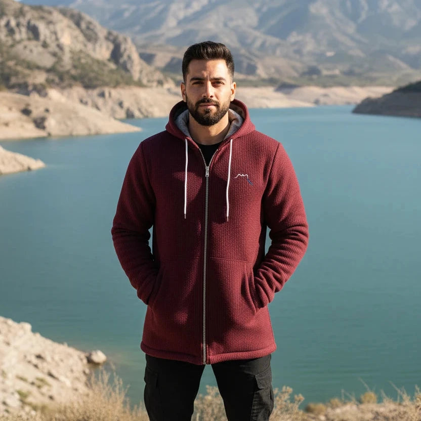 homme portant la veste polaire longue chili coloris rouge bordeaux devant un lac en navarre